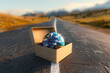 Open cardboard boxe with Earth globe on the road. International package delivery concept.