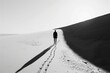 A solitary figure is seen walking in a vast desert landscape, portraying a sense of isolation and journey