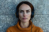 Fototapeta  - Portrait of a woman with stern expression wearing headphones against a textured backdrop