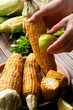 Female hands rubbing a roasted sweet corn cob with lime