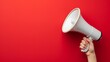 Hand holding a megaphone on a red background. Copy space.