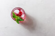 Raspberry drink with ice in a glass on a light background