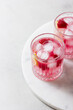Raspberry cocktail with ice in a glass on a light background