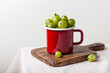 Fresh green gooseberry berries in a red enamel mug