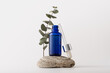 Blue glass serum bottle for organic cosmetic on natural stone podium