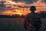 Fototapeta Do akwarium - Landscape with WWII soldier on his back, field in the background with sunset.