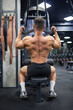 Strong, muscular bodybuilder exercising with training apparatus in gym. Back view of anonymous man wearing black shorts, building back muscles, working out. Sport, lifestyle, bodybuilding concept.