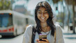 © Théo - Excited South Asian woman smiling while using a smartphone, showcasing the joy of technology and connection.