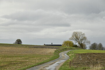 Petite route de campagne étroite entre les champs sous un ciel gris à Ghislenghien (Ath)