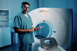 Fototapeta  - Medium long shot of biracial doctor standing by MRI scanner holding digital tablet looking at camera, copy space