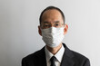 マスクをしてメガネをかけたスーツ姿の日本人の中年男性のポートレイト