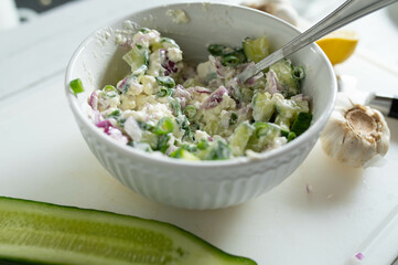 Wall Mural - Cucumber salad with feta yogurt sauce, onions and chives in a bowl