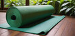 A yoga mat is laying on a green mat in a room with a garden background.