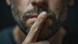 A man makes a quiet shh gesture with a finger on his lips, symbolizing taboo topics, censorship, or the freedom of speech. 