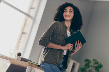 Poster - Portrait of pretty young woman hold book brainstorming wear khaki shirt modern interior house indoors