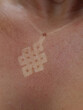 CLOSE UP, DOF Mark of necklace pendant on reddish skin of an unknown young woman. Careless lady forgot to apply protective sunscreen before summer sunbathing, which resulted to reddened and burnt skin