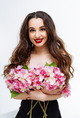 Wall Mural - A woman is holding a bouquet of pink and white flowers. She is smiling and wearing red lipstick.