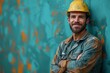 A confident construction worker with stubble, wearing a soiled hardhat, stands with crossed arms against a turquoise backdrop