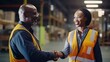 © jureephorn - African American manager who is touring a factory with her co-workers Happy holding hands with workers