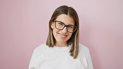 Wall Mural - Young, cool and confident! a beautiful hispanic woman, lucky in life, standing in front of an isolated pink wall, wearing glasses and a joyful smile.