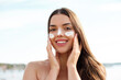 Beautiful woman applying cream sunscreen on tanned face. Sunscreen. Skin and body care. The girl uses a sunscreen for her skin. Portrait of a female holding suntan lotion and moisturizing sunscreen
