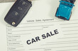 Blue toy car, key and vehicle sales agreement. Inscription car sale. Sales and buying new or used car