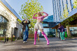 © Kitreel - Vibrant Outdoor Scene Capturing Young Adults Joyfully Dancing In An Urban Setting, Showcasing A Mix Of Retro Fashion and Emphasizing Themes Of Youth, Culture, And Friendship Under A Clear Blue Sky.