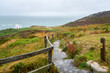 Narrow fenced path with steps leading to a clifftop viewpoint on a lighthouse along the coast of north Wales on a foggy summer day