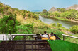 Back view of Happiness caucasian couple relaxing together on comfortable seats with beautiful view of nature at balcony on a hill near the riverbank. Happy love couple sitting together near riverside.