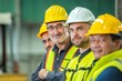 © BESTIMAGE - Group of happy workers wearing hard hats and safety vests in a factory