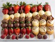 A plate of assorted desserts with strawberries and chocolate. The plate is white and has a variety of desserts including brownies, cupcakes, and fruit