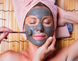 woman getting a facial mask of clay on her face