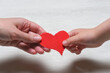 World mother day concept background. Mother and son hands with red shape heart close up.