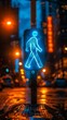 Blue neon crosswalk sign at night in the rain with blurred orange and yellow lights in the background.