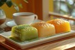 A white rectangular plate with three pastries, one green matcha mochi cake and two yellow chard petal cakes on it,