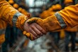 © Larisa AI - Close up of two workers shaking hands wearing yellow gloves against an industrial blurred background, representing teamwork and dedication