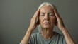   An older woman places both hands on her head