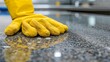   A pair of yellow gloves sits atop a granite counter, adjacent to a single yellow glove on a black counter