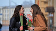 two happy girls, students, friends with flowers in their hands, laughing