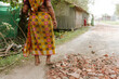 old indian woman in traditional sari walking on dirt road in a village in rural India. Concept of poverty and infrastructure and India development