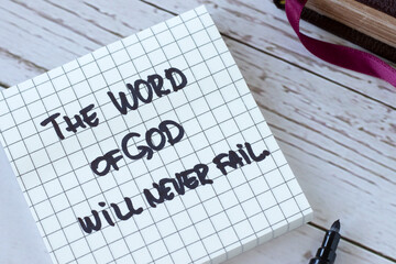 Wall Mural - The Word of God will never fail, handwritten quote with holy bible on wood. Close-up. Inspiring Christian message about Jesus Christ's faithful promise, purpose, and plan. Biblical concept.