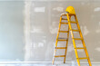 © nutalina - A construction ladder and a helmet stand against the wall. Apartment renovation and decoration concept