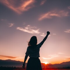 Wall Mural - silhouette of a young woman with raised hand on background mountains and sunset. freedom, freedom concept.