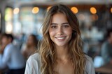 Fototapeta  - A young woman with a joyful smile sitting in a cafe, radiating warmth and friendliness