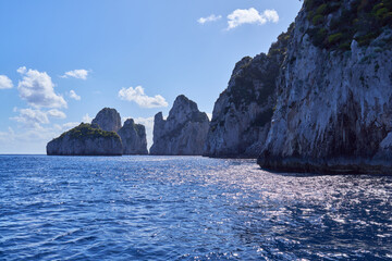 Wall Mural - The coastline of the island of  Capri, with Faraglioni di Capri rock formations in the background, Campanian Archipelago, Italy