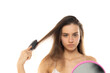 A young woman brushes her hair in the mirror on a white background