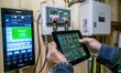 © Business Image - Smart meter, smart metering. A technician using an electric meter to Protective of the home's electrical system while holding up his tablet.