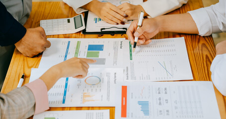 Two people are looking at a graph on a table. One of them is holding a pen. The graph shows a comparison of different data points