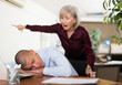 Man office worker sleeping on table during work day. His chief senior woman standing next to him and shouting at him.