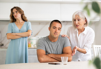 Wall Mural - Adult woman during family quarrel with elderly woman and adult man in kitchen